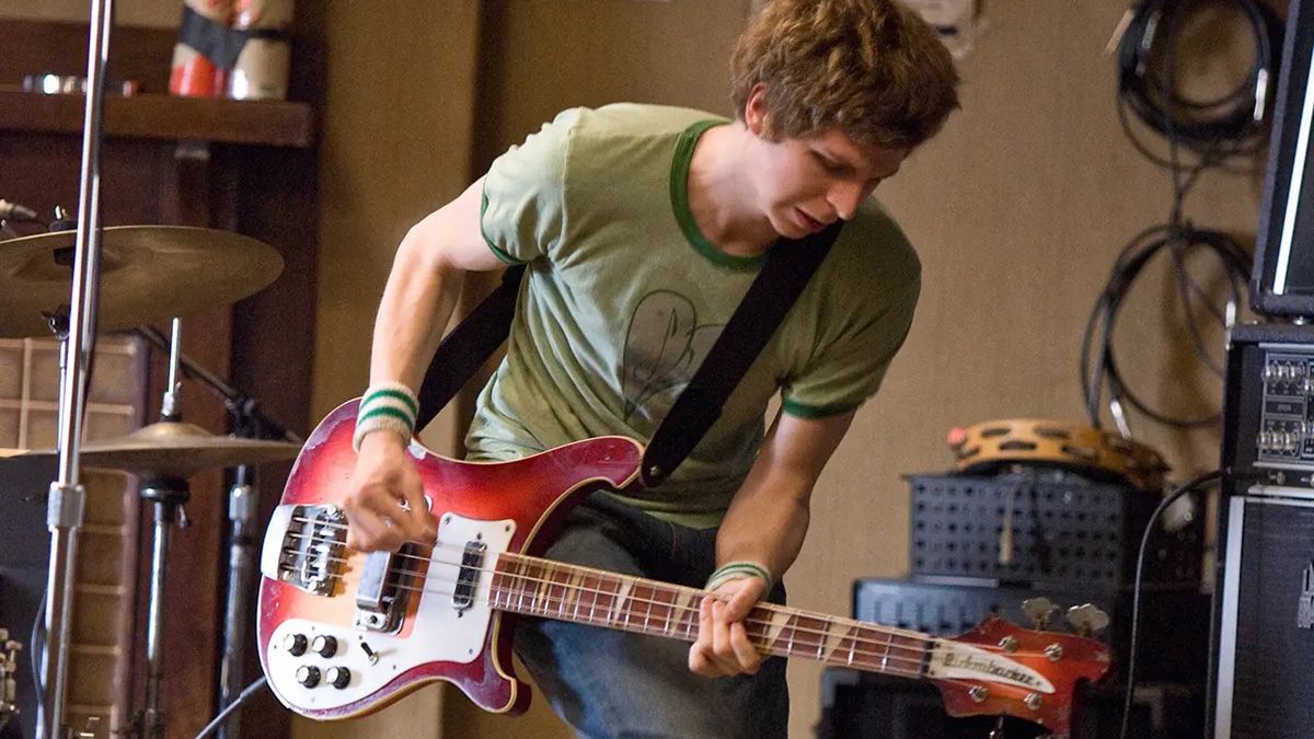 Scott Pilgrim playing a red bass guitar in the rehearsal room