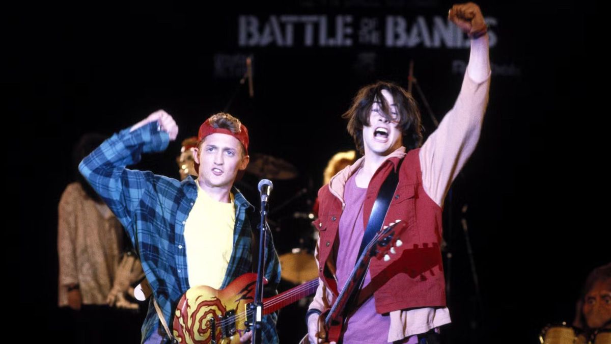Bill and Ted raising their arms onstage with their guitars